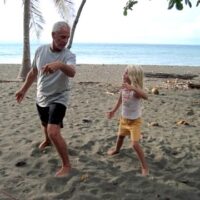 A grandfather and grand daughter play Tai Chi on beach