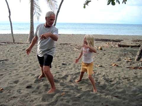 A grandfather and grand daughter play Tai Chi on beach