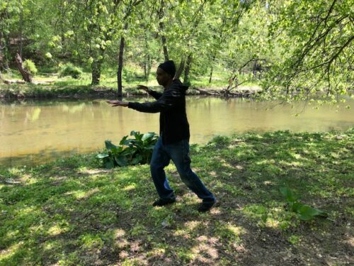 Teaching Team member, Charles Peters practices Single Whip beside a forest creek.